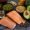 Legumes, broccoli, fruit, and salmon placed on a black cement floor. Top view.